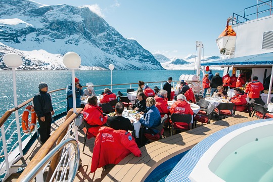 Die Gäste genießen das BBQ an Deck des Expeditionskreuzfahrtschiffs bei strahlender Sonne in der Antarktis Mittagessen in strahlender Sonne an Deck des Expeditions-Kreuzfahrtschiffs während der Kreuzfahrt